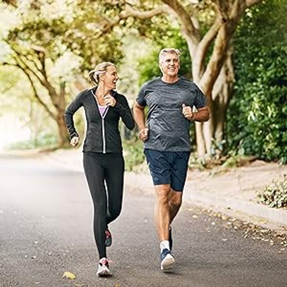 middle aged couple happily running in park